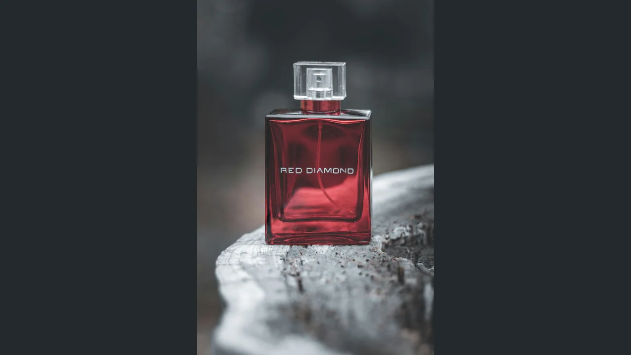 A red perfume bottle with a clear square cap and RED DIAMOND lettering, shown in the original photograph