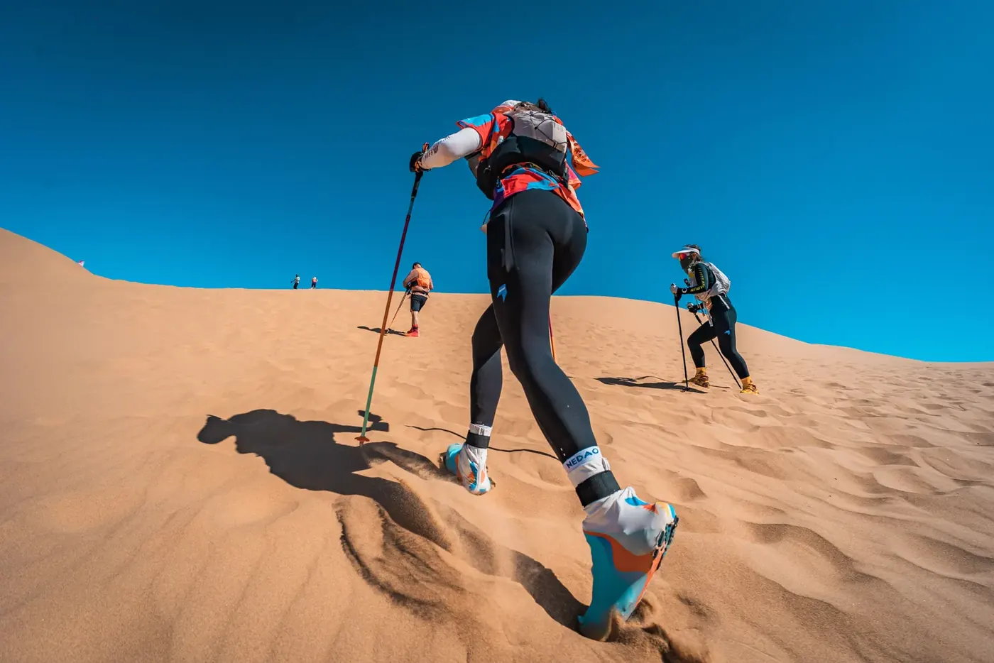 Original photo of trail runners climbing a desert sand dune